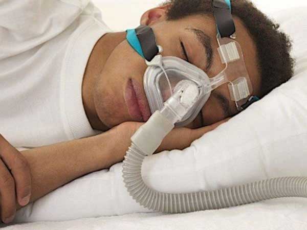 A man sleeping with a continuous positive airway pressure device to help with his sleep apnea