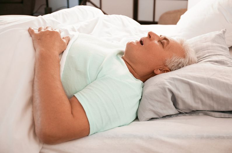Mature man snoring while sleeping in bed