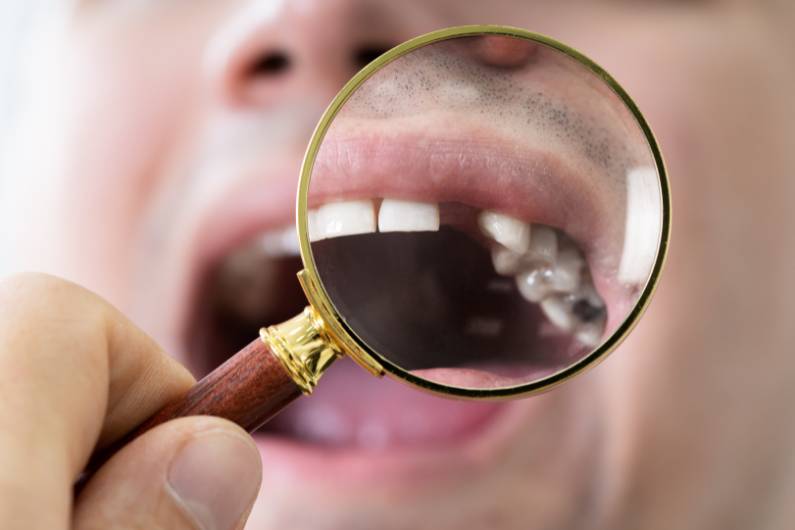 Someone using a magnifying glass to check missing teeth